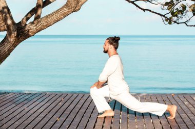 Adam beyaz giysili ahşap iskele yoga meditasyon