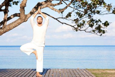 Adam beyaz giysili ahşap iskele yoga meditasyon