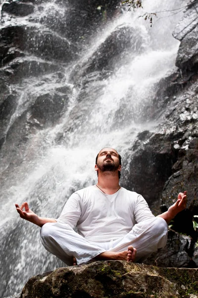 熱帯の滝で瞑想ヨガの岩の上に坐っていた男 — ストック写真