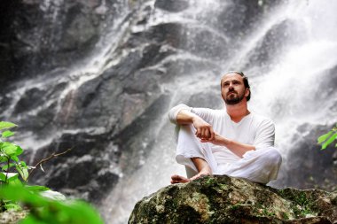 Tropik şelale, meditasyon Yoga kayaya oturan adam