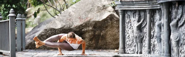 Mujer joven haciendo yoga en templo abandonado en plataforma de madera. Practicar . —  Fotos de Stock