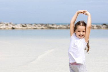 Sahilde mutlu bir çocuk. Paradise tatil kavramı kız mavi sığ su ve temiz gökyüzü kum plajındaki oturma