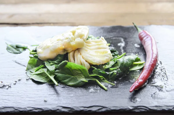 Filetto di pesce bianco con peperoncino su spinaci fritti. Fondo grigio . — Foto Stock