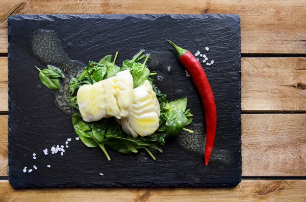 White fish fillet with chili on fried spinach. Gray background. — Stock Image White fish fillet with chili on fried spinach. Gray background. Stock Image