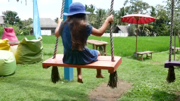 欧洲小女孩玩木秋千幸福。亚洲, 巴厘岛。印度尼西亚 — 图库视频影像
