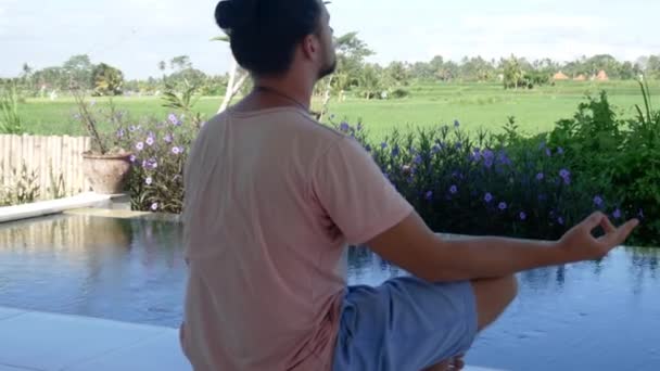 Мужчина медитирует на йоге в экзотическом саду — стоковое видео