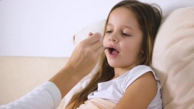 Anne ya da tıp hasta kızı yatakta şurubu veren doktor