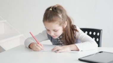 Bir çocukla bir tablet ve bir kitap. Bir kağıt kitap ve bir e-kitap ile bir kız öğrenci öğrenir.