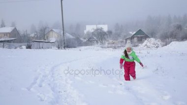 Kız çocuk karla kaplı yolda çalışır. Aktif tatiller bir bulutlu kış günü çocuklar için.