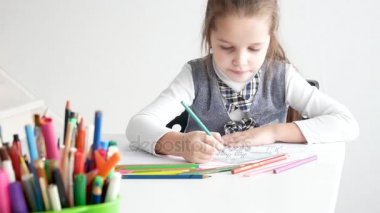 Küçük kız bir resim beyaz oda üzerinde çizim. 7 yaşında bir kağıda evde boyama ve çizim kız.