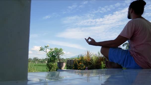 Mens in yoga lotus zitten poseren op groen gras in de wei en mediteert. — Stockvideo