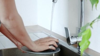 Mutfak lavabosunda bulaşık yıkayan kadın.