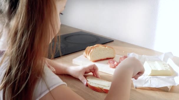 Kleines Kind backt Sandwich mit Butter und Wurst — Stockvideo