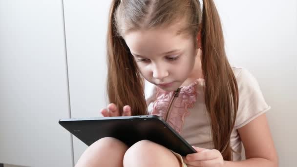 Fille émotionnelle joue dans les jeux vidéo en utilisant une tablette. Portrait d'enfant avec gadget électronique — Video