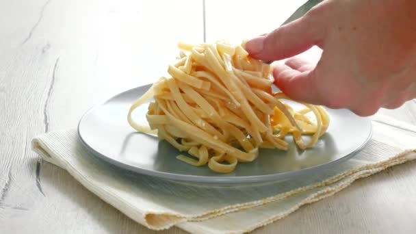 Poner espaguetis para cocinar con pinzas. Cocinar espaguetis concepto. Mano femenina poniendo espaguetis en plato — Vídeo de stock