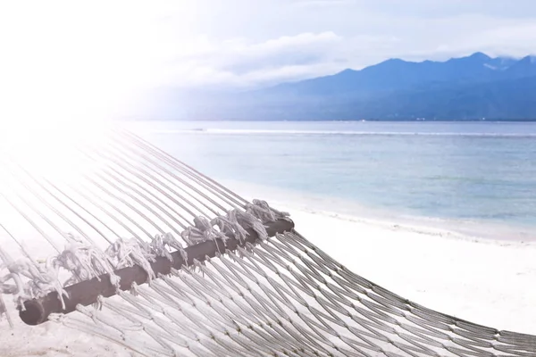 バリ島の紺碧の海の背景に砂浜でハンモック。インドネシア ギリ ・ トラワンガン島の海岸. — ストック写真