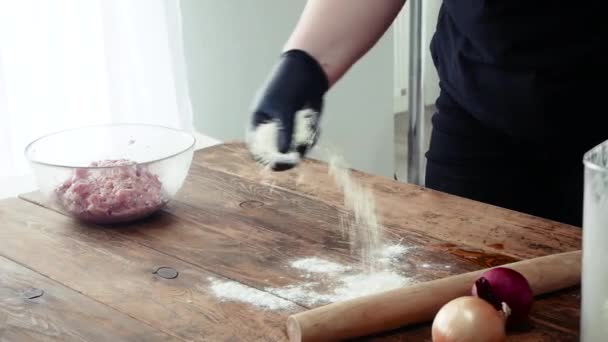 Fast food chef mains dans les gants déploie filo pâte feuilletée coupe rouleau, tarte ou gâteau sur une planche de bois. — Video