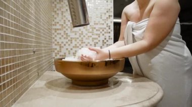 Buz banyosu şok terapisi. Dişi, sauna banyosu yaptıktan sonra yüzünü buzla yıkar..