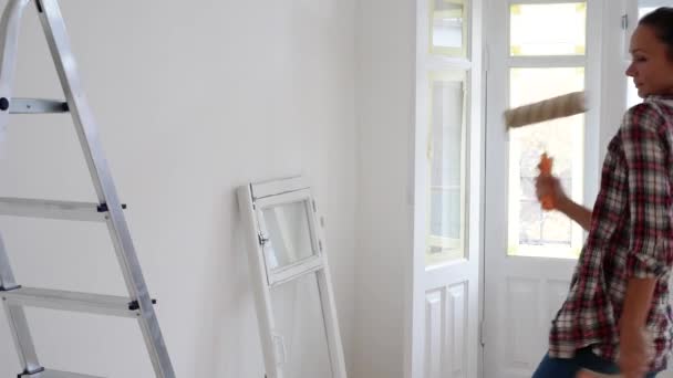 Girl makes repairs in the apartment and dancing, woman doing wall painting — Stock video