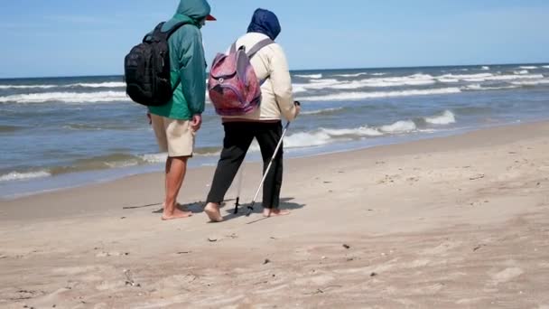 Oude echtpaar man en vrouw die bezig zijn met Nordic walking, wandelen op het strand. Palanga, Litouwen. Achteraanzicht. — Stockvideo