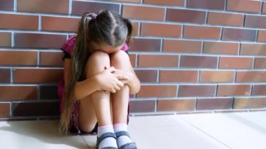 Child abuse. Little girl crying, sitting on the floor