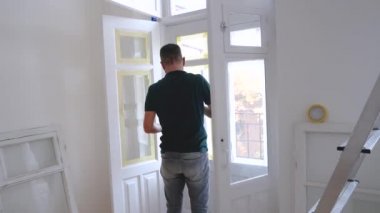 Kapıyı ya da pencereyi fırçayla boyayan adam. Lastik tamir ediliyor.