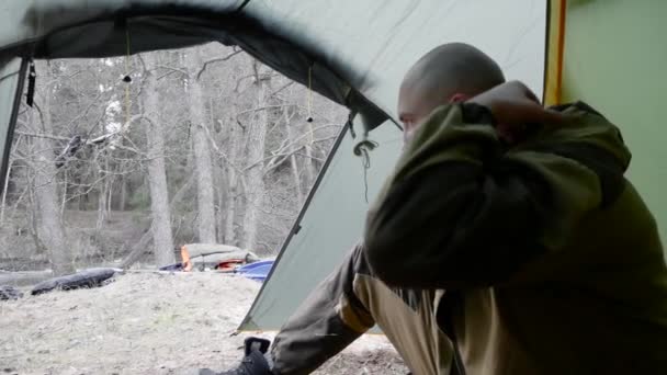 Een jonge serieuze man zit in een campingtent. Geniet van een prachtig uitzicht en denken. Wandelavontuur. Sportreis herfst — Stockvideo
