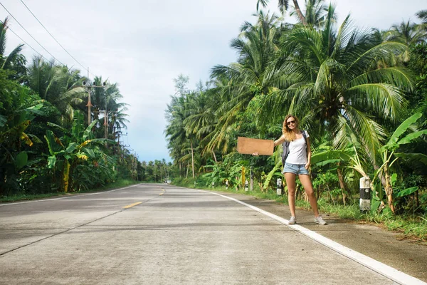 Jeune femme auto-stop le long d'une route — Photo