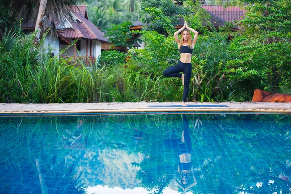 Молодая женщина практикует йогу в бассейне — стоковое фото