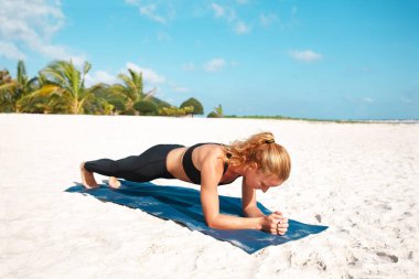 Genç kadın plajda yoga yapıyor.