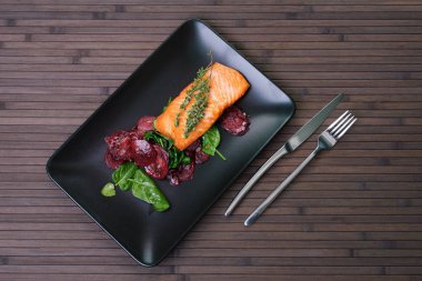 Siyah plaka üzerinde pişmiş kırmızı pancar ile Somon fileto.