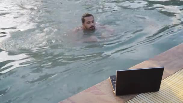 Jeune homme bavarder avec ordinateur portable près de la piscine à l'hôtel — Video