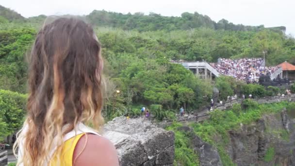 BALI: niña de pie en el acantilado y mirando al océano en el templo de Uluwatu — Vídeo de stock