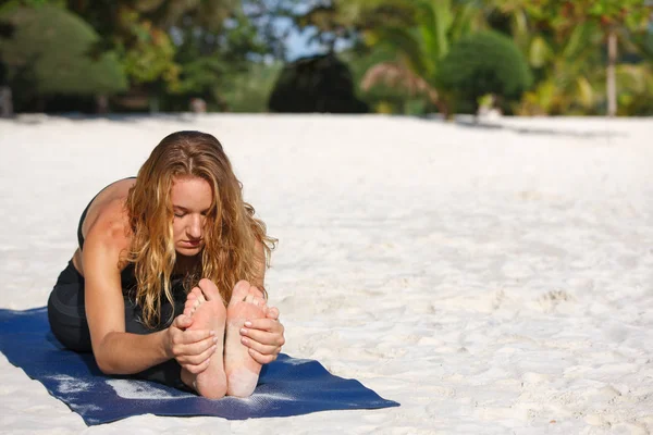 Ung kvinna utövar yoga på stranden — Stockfoto