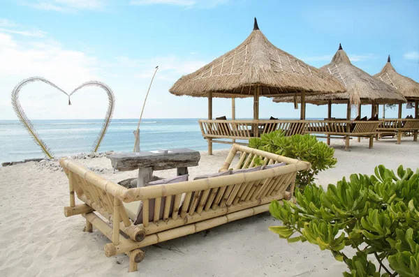 Beautiful send beach of Gili Travangan island with ocean on a background and two chairs under umbrella, Indonesia — Stock Photo, Image