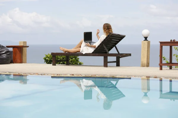 Εργασία στην παραλία. Επιτυχημένη γυναίκα των επιχειρήσεων λειτουργεί σε απευθείας σύνδεση στο διαδίκτυο, χρησιμοποιώντας φορητό υπολογιστή σε εξωτερικούς χώρους. — Φωτογραφία Αρχείου