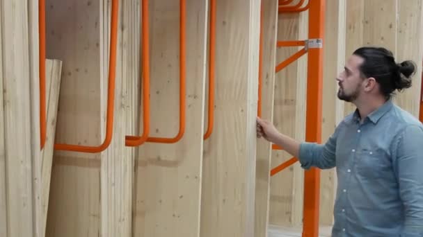 Jongeman selecteren van houten planken in een ijzerhandel of magazijn — Stockvideo