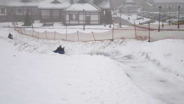 Ευτυχισμένος κορίτσι βόλτες και χαμογελαστά snowtube σε χιονισμένους δρόμους — Αρχείο Βίντεο