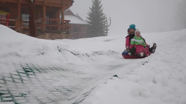 Glad tjej och mather Rider snowtube på snöiga vägar — Stockvideo