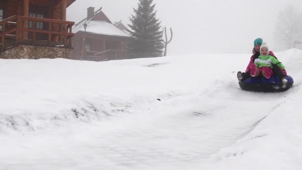 Glad tjej och mather Rider snowtube på snöiga vägar — Stockvideo