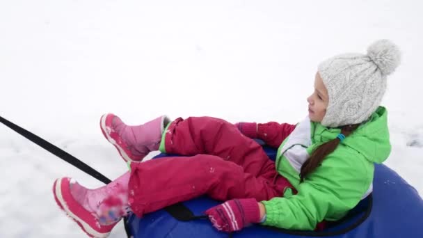 Menina feliz passeios e sorrindo snowtube em estradas nevadas — Vídeo de Stock