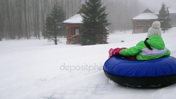 Glad tjej rider och leende snowtube på snöiga vägar — Stockvideo