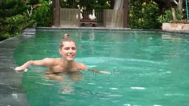 Gelukkig jonge vrouw ontspannen bij het zwembad van het luxe — Stockvideo