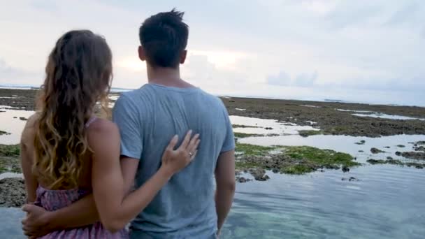 Atractiva pareja abrazándose durante el atardecer cerca del océano. Luna de miel . — Vídeos de Stock