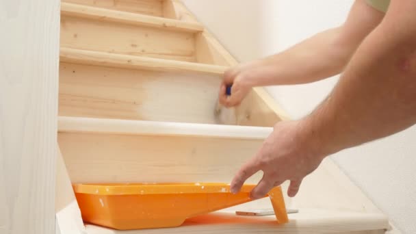 Человек рисует деревянную лестницу кистью в белом — стоковое видео