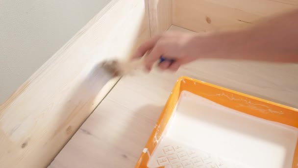 Hombre pinta una escalera de madera con un pincel en blanco — Vídeo de stock