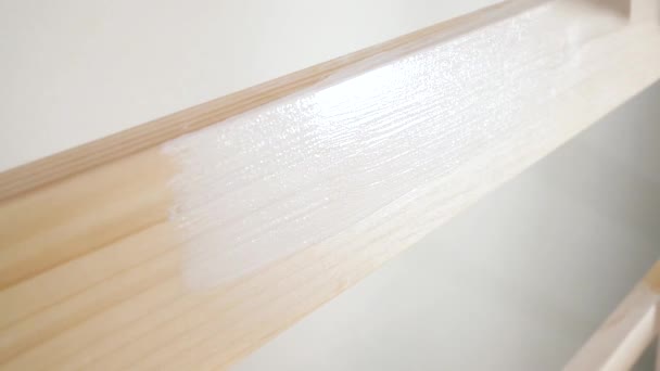 Hombre pinta una escalera de madera con un pincel en blanco — Vídeo de stock