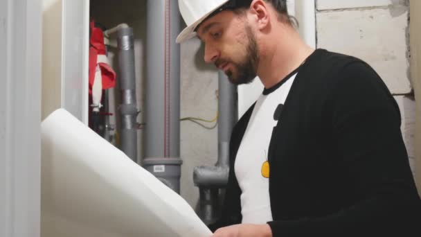 Maître constructeur en casque avec dessins de conception sur chantier. Travailleur avec documentation de construction sur le site du projet — Video