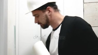 Baret inşaat sahasında tasarım çizimleri ile baş mimar. Alt proje sitesinde inşaat belgelerine ile