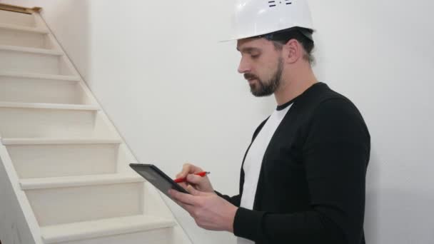 Master builder in hard hat with design drawings at construction site. Worker with construction documentation at project site — Stock Video